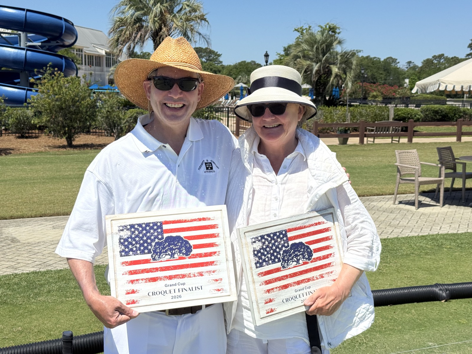 Two players in white and sun hats smile while holding their Grand Cup Croquet Finalist 2026 plaques.